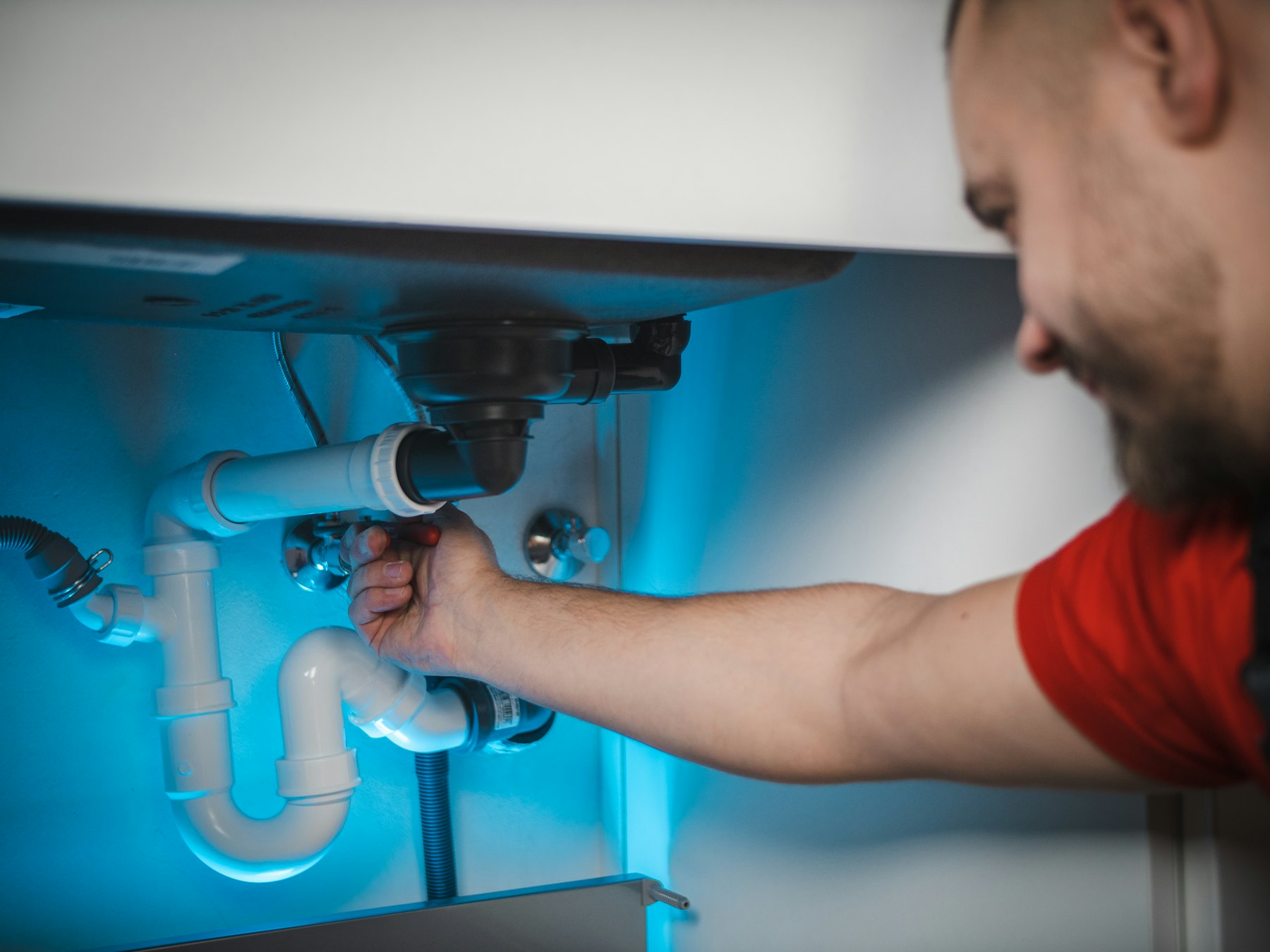 PlumbServ engineer repairing pipework under a sink